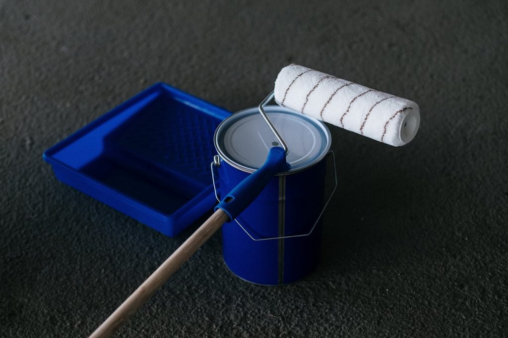 a-paint-roller-on-the-paint-can-9222200 Close-up of a paint can, roller, and tray on a textured floor, perfect for DIY projects.